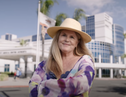 A woman in a floral dress stands in front of Loma Linda University Healthy Murrieta Center