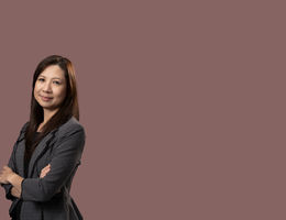 Asian woman in black and white business suit standing with arms crossed