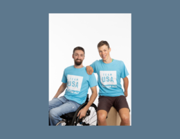 two Caucasion males, one in a wheelchair in blue t-shirts
