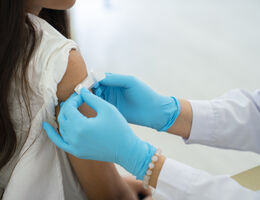 Doctor applies bandage to girl's arm following an immunization