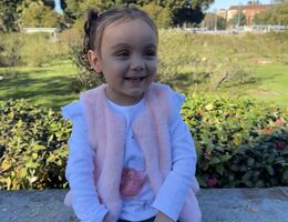 Alaia Pacheco sitting on a bench and smiling while looking off camera
