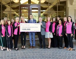 a group of people stand together holding a large check