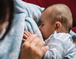 Mother breastfeeding her baby on the sofa