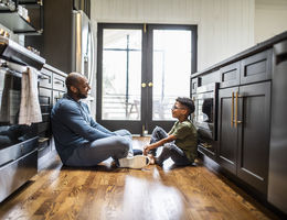 Father talking with tween son in residential kitchen 