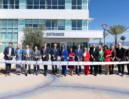 LLUH leaders pose for photo behind long ribbon with large scissors