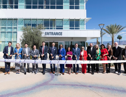 LLUH leaders pose for photo behind long ribbon with large scissors