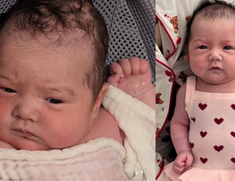 a baby in a pink dress with red hearts