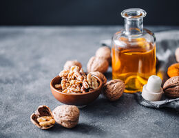 walnuts spread around a small glass bottle of oil.
