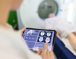 Neurologist examining patient's CAT scan images on digital table in clinic