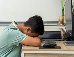 Teenage boy sleeping with his head down on a desk