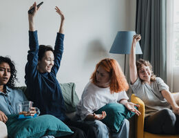 Four friends gather in a comfortable living room, animatedly watching sports. They express excitement, showing various emotions as they cheer for their favorite team.