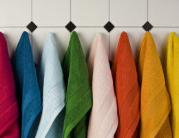 Multi colored towels hanging in a row on the wall 