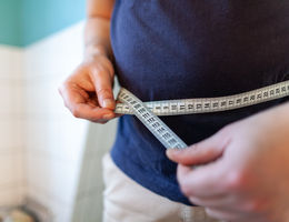 Man holding a measuring tape to his waist