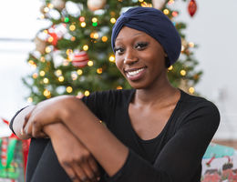 Woman with headscarf sitting in front of Christmas tree