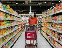 Woman shopping in supermarket aisle lined with processed foods