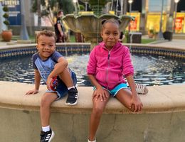 Young Black girl and boy sitting on a fountain edge