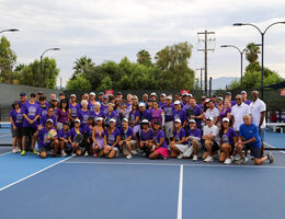 Attendees wearing purple shirts gather on pickleball court 