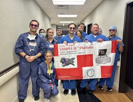Cardiology team stand together in a hallway holding a large banner that reads “VARIPULSE Platform.” 