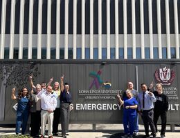 group of medical staff celebrating their recognirion outside in front of Emergency room signage