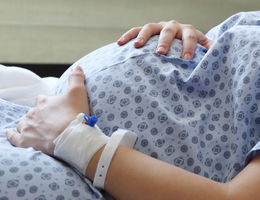 pregnant women in hospital gown holding baby