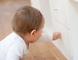 Baby girl opening a drawer with curiosity. Risks at home with little children.