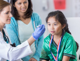 Head Games: How to identify a concussion Young girl at the doctor's office with her mother. Doctor is examining her eyes following a hit.