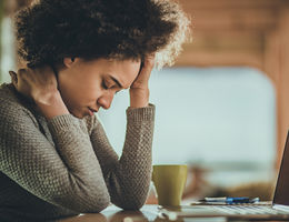 VIDEO: When does mental health get physical? women rubbing her head while sitting in front of a computer screen