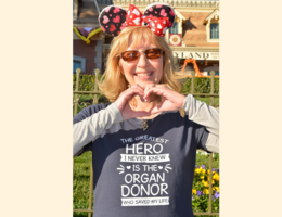 Julie Hutchinson makes a heart with her hands while wearing an organ donor appreciation shirt