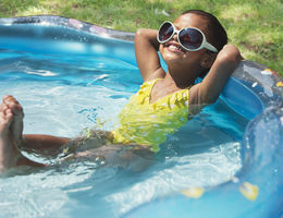 Hispanic girl relaxing in kiddie pool 