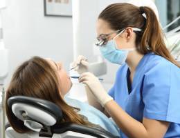 Female dentist cleans the teeth of a female patient in a dental office.