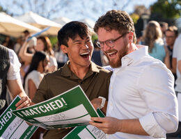 Asian man and Caucasian man outside smiling as they learned their fate at match day 2026