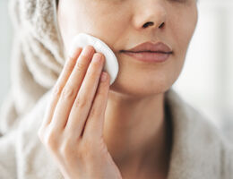 Woman swiping cotton pad across skin
