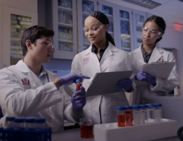 a group of people are in a medical setting looking over a vile of medication 