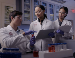a group of people are in a medical setting looking over a vile of medication 