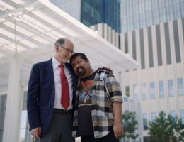 a man in a suit is hugging another man while smiling