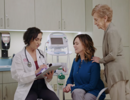 a doctor is speaking with a patient and their loved one in a medical setting
