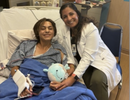 Patient Jesse Campos smiles while on hospital bed next to Dr. Tanya Minasian