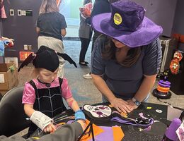 volunteer helps child with festive craft