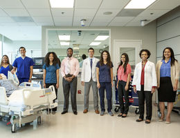 Loma Linda University staff of nurses, physicians and faculty stand in the middle of a patient's room. 