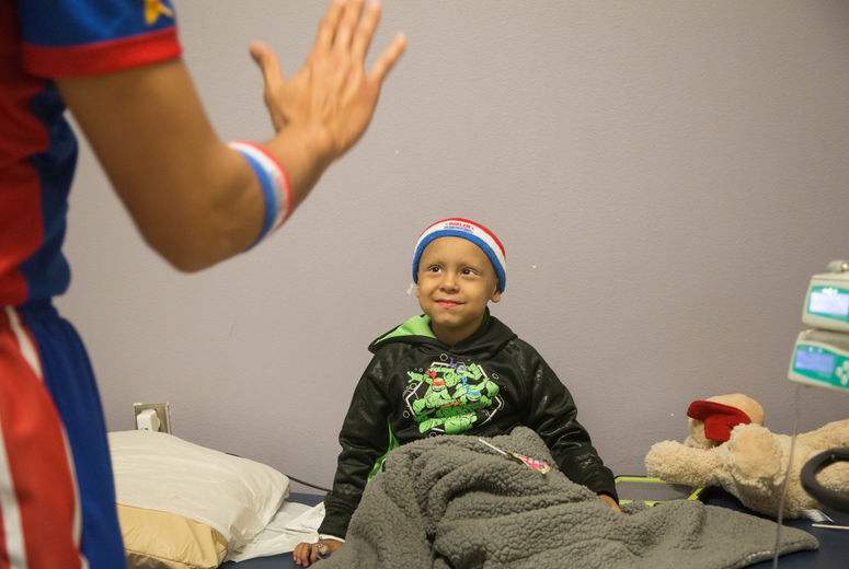 Harlem Globetrotter "Zeus" McClurkin gives a young chemotherapy patient a head band and a high-five for encouragement. The Harlem Globetrotters brought Valentine's Day cheer to children at the Loma Linda University Children's Hospital Hematology/Oncology Clinic on Wednesday, February 14, 2018, in Loma Linda, California.