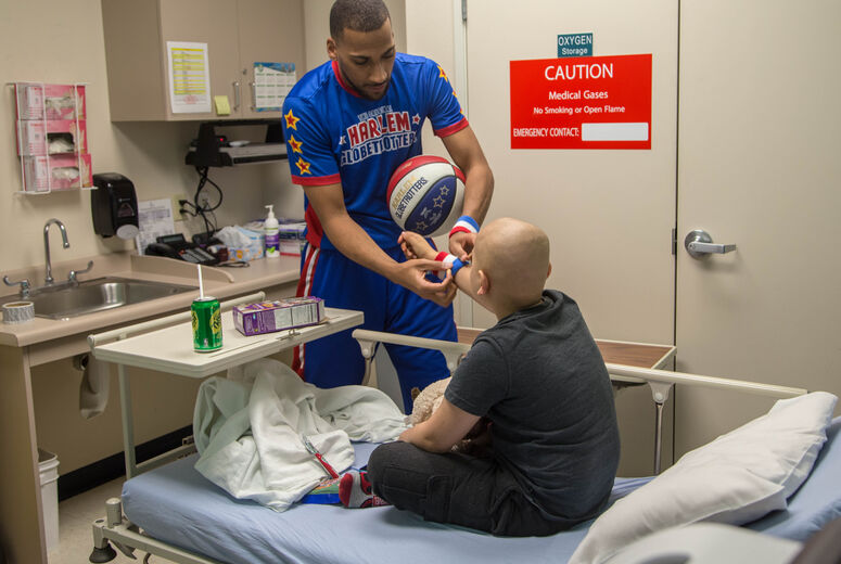 Harlem Globetrotter "Zeus" McClurkin gives a young chemotherapy patient one of his wristbands for encouragement. The Harlem Globetrotters brought Valentine's Day cheer to children at the Loma Linda University Children's Hospital Hematology/Oncology Clinic on Wednesday, February 14, 2018, in Loma Linda, California.