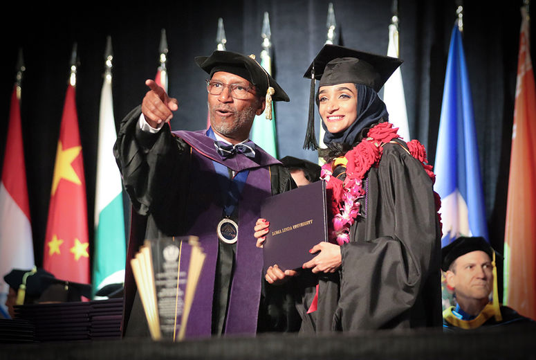 Dean Jackson acknowledges the applause as a graduate receives her diploma.