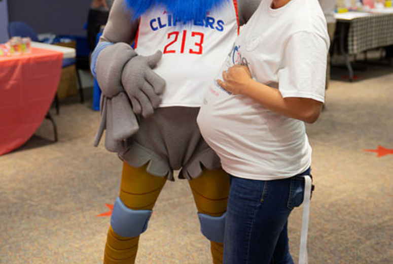 Pregnant woman and mascot take photo together