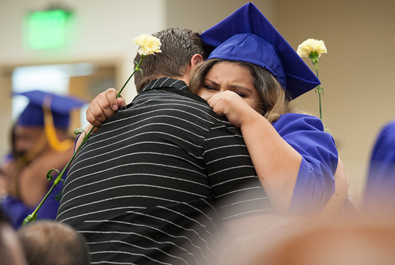 Medical assistant graduate Edilma Ramirez presents a carnation and hug to one of her supporters.