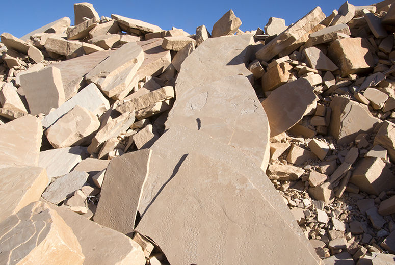 Fragments of Coconino Sandstone in an Arizona quarry. Intricate patterns adorn the faces of the large pieces in the foreground, remnants of ancient geological mysteries.