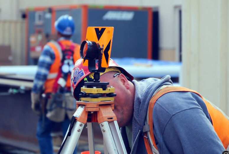 Eddie uses a circular prism to check the plumpness of the new building.